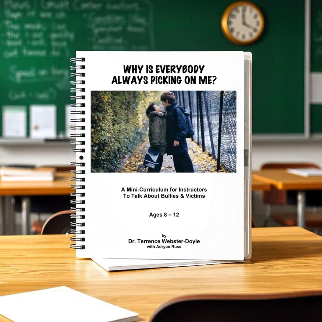 Spiral-bound mini-curriculum titled "Why Is Everybody Always Picking On Me?" for ages 8-12 about bullies and victims, by Dr. Terrence Webster-Doyle, on a wooden school desk with a classroom background.
