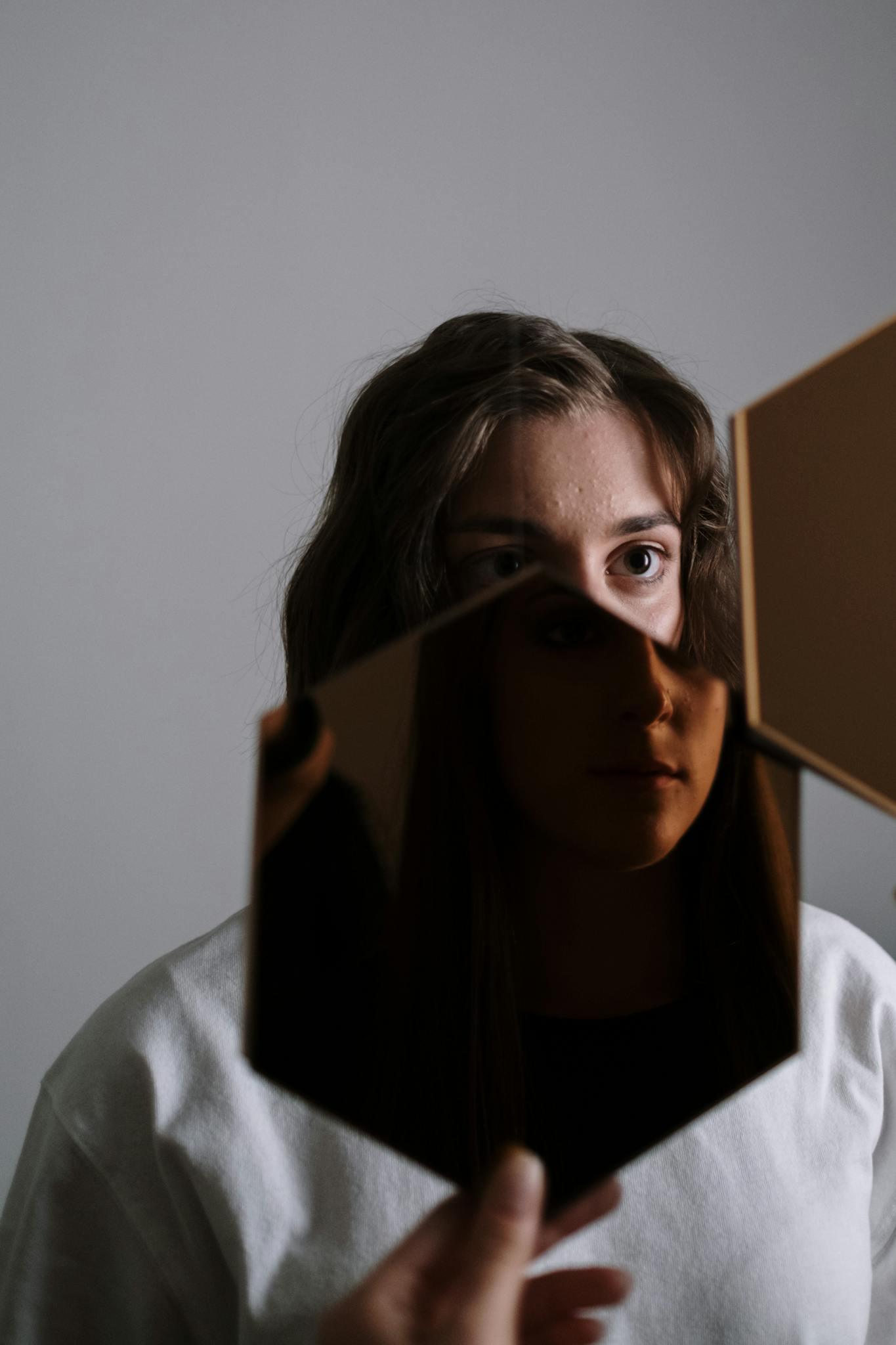 A unique portrait of a woman reflected in a broken mirror, evoking emotion and introspection.