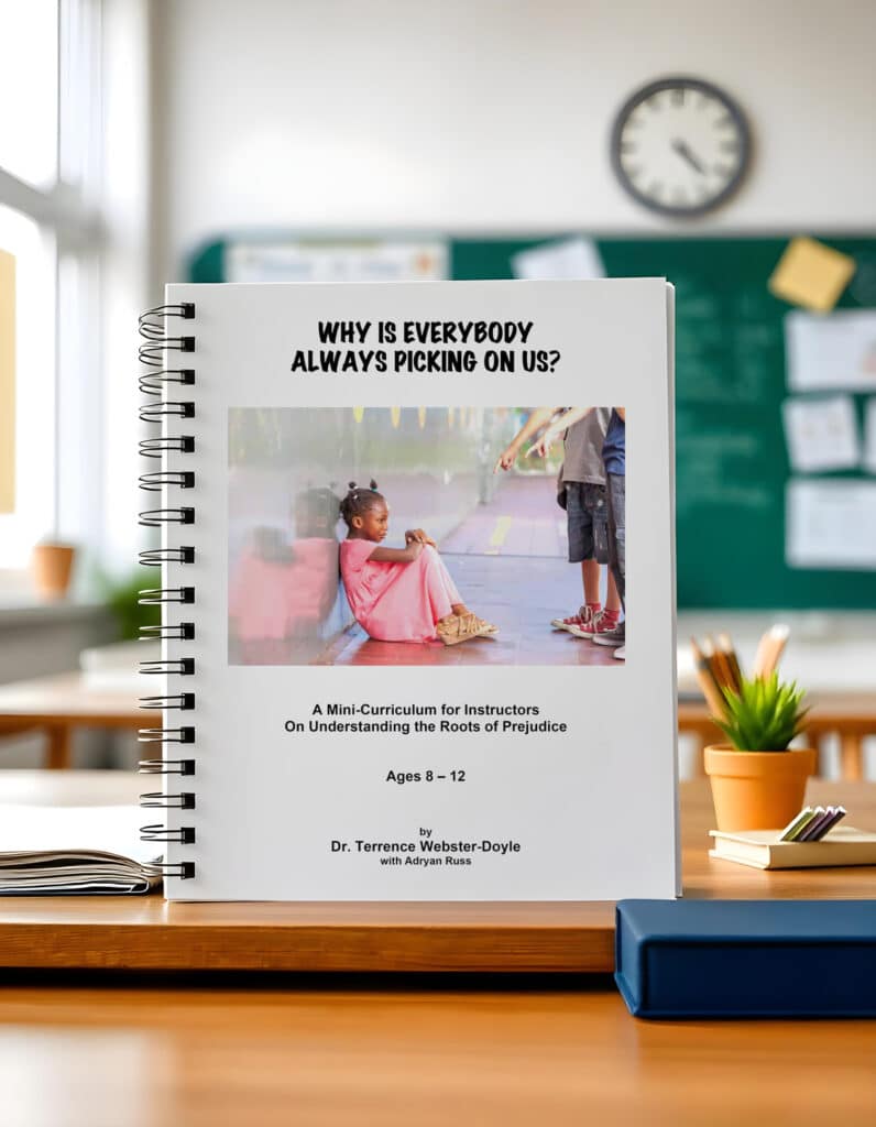 Spiral-bound book titled "Why Is Everybody Always Picking on Us?" designed for instructors, focusing on understanding the roots of prejudice for ages 8-12, displayed on a wooden desk in a classroom setting.