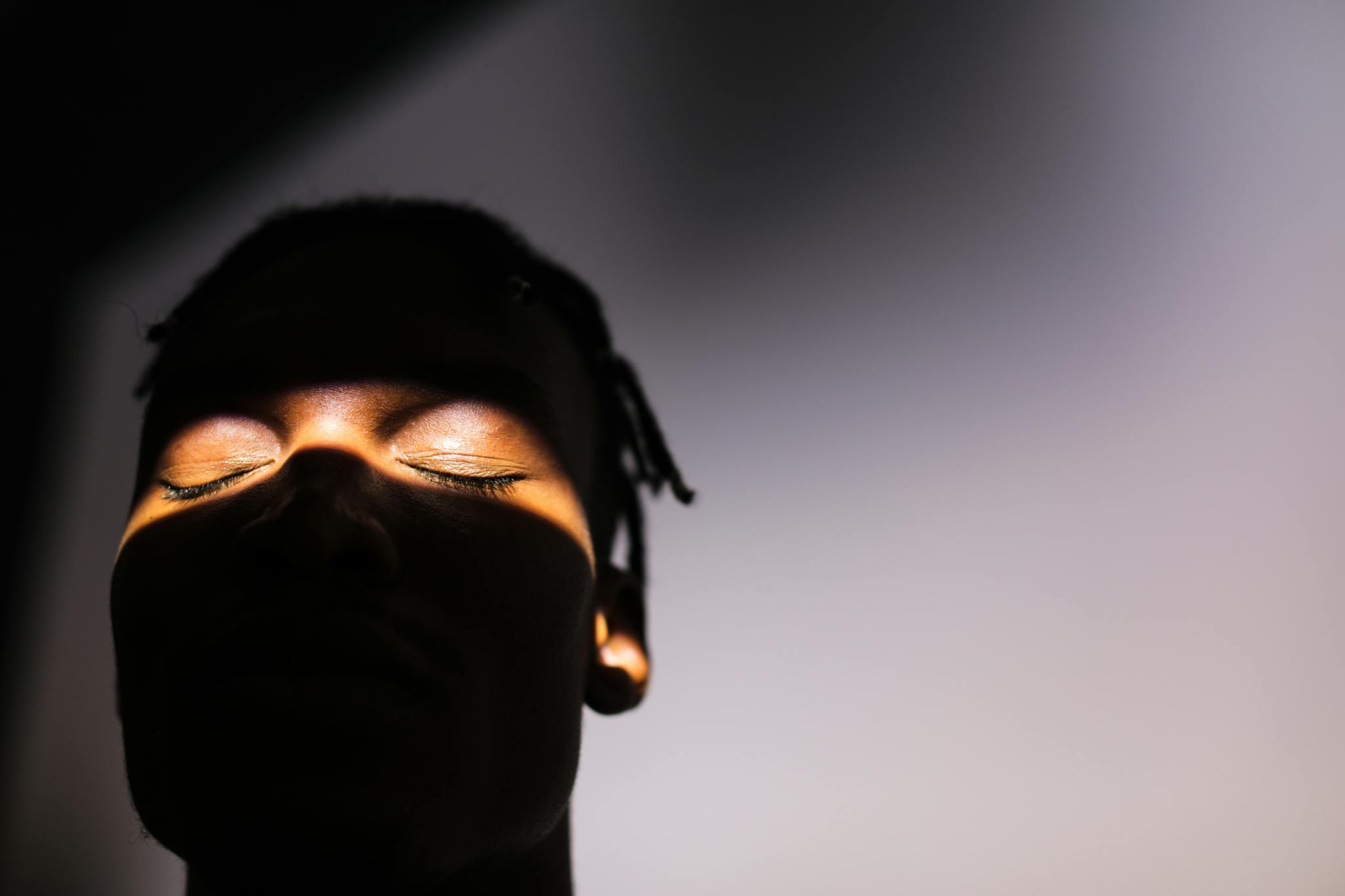 Silhouette of a man's face with dramatic lighting highlighting closed eyes.