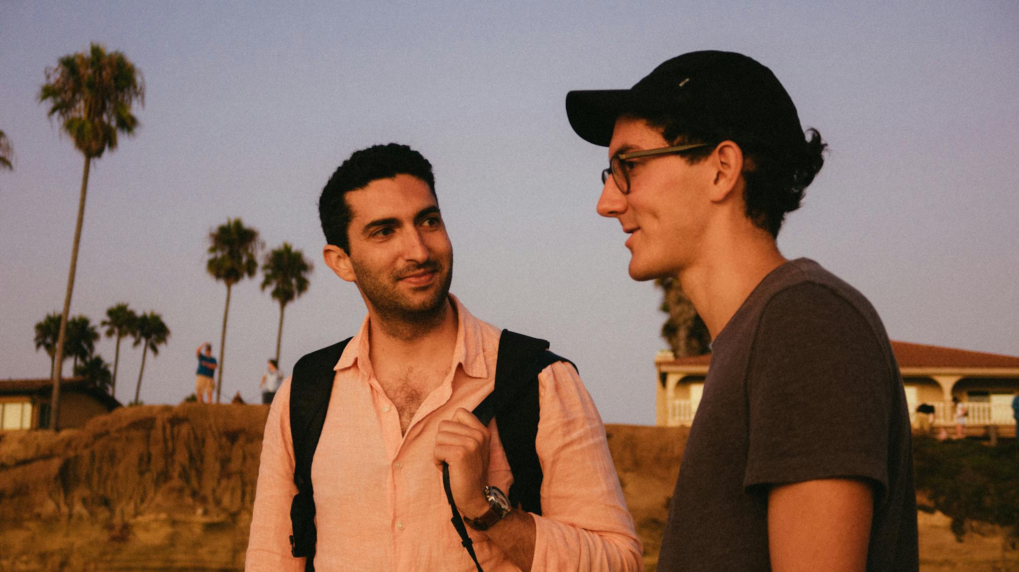 Two friends chatting outdoors at sunset, creating a warm and relaxed atmosphere.